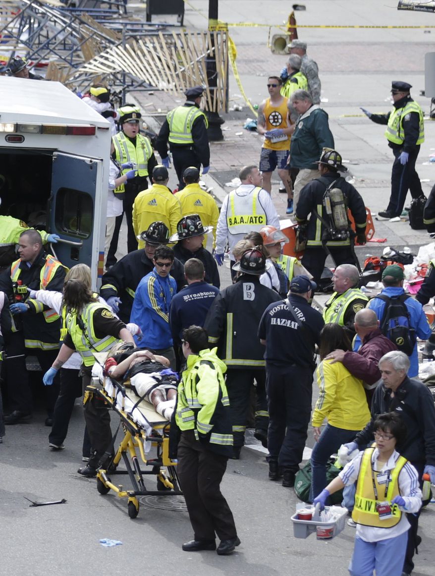 FILE - In this Monday, April 15, 2013 file photo, medical workers aid injured people at the finish line of the 2013 Boston Marathon following an explosion in Boston. Runner Lucas Carr can be seen in the upper center of the photo in the yellow Boston Bruins shirt. Carr, an Army Sergeant who served in the middle east, assisted several of the injured by applying tourniquets. (AP Photo/Charles Krupa, File)