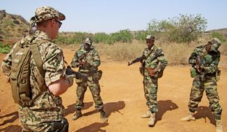 A Swedish instructor watches as Malian soldiers practice arming their weapons in the village of Koulikoro, outside Bamako, Mali. In preparation for the final pullout of French troops from Mali, a European Union team has started training Malian soldiers to battle jihadists. (Associated Press)