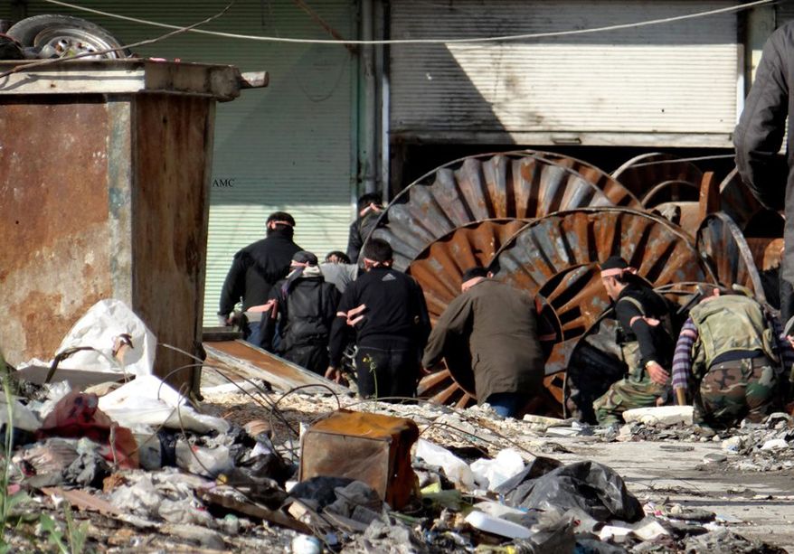 This citizen journalism image provided by Aleppo Media Center AMC which has been authenticated based on its contents and other AP reporting, shows members of the free Syrian Army hiding behind scrap metal during an attack against Syrian government forces, in the neighborhood of al-Amerieh in Aleppo, Syria, Sunday, April. 21, 2013. (AP Photo/Aleppo Media Center AMC)