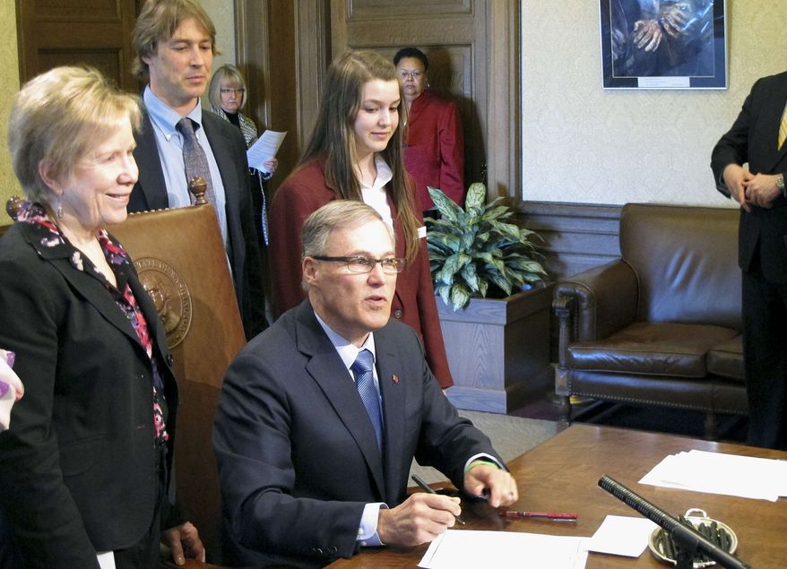 Gov. Jay Inslee, seated, signs a measure to make state statutes gender-neutral, joined by bill sponsor Sen. Jeannie Kohl-Welles, left, on Monday, April 22, 2013, in Olympia, Wash. The measure is the final installment of a multiyear project to replace thousands of references to male-centric words in state law with gender-neutral terms. (AP Photo/Rachel La Corte)