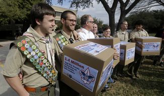 **FILE** James Oliver (left) hugs his brother and fellow Eagle Scout, Will Oliver, who is gay, as Will and other supporters carry four boxes filled with a petition to end the ban on gay scouts and leaders in front of the Boy Scouts of America headquarters in Dallas on Feb. 4, 2013. (Associated Press)