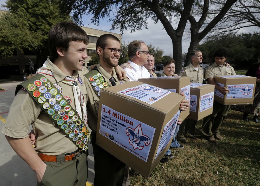 **FILE** James Oliver (left) hugs his brother and fellow Eagle Scout, Will Oliver, who is gay, as Will and other supporters carry four boxes filled with a petition to end the ban on gay scouts and leaders in front of the Boy Scouts of America headquarters in Dallas on Feb. 4, 2013. (Associated Press)