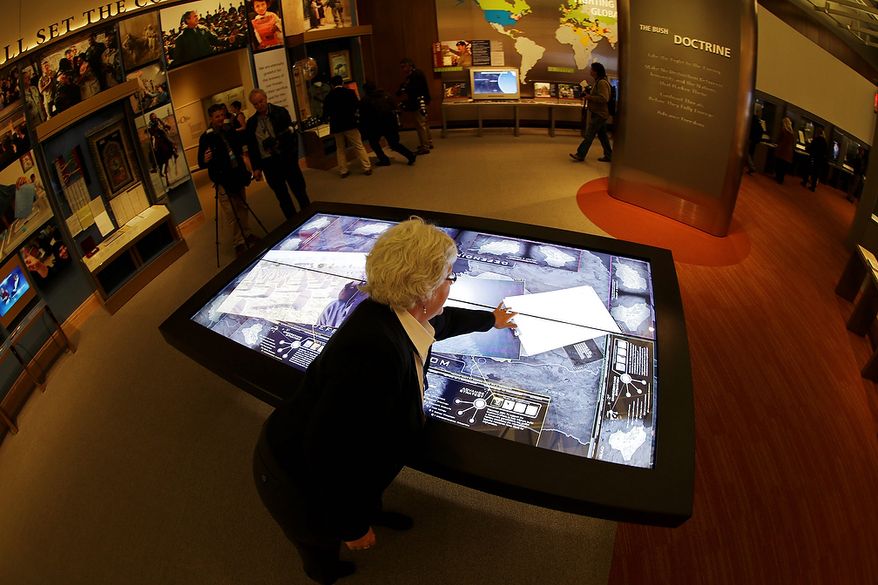 Docent Patricia Flynn demonstrates an interactive with information about conflicts in Afghanistan and Iraq during a tour of the George W. Bush Presidential Center Wednesday, April 24, 2013, in Dallas. More than 8,000 people are expected to attend the invitation-only dedication of the center, Thursday, April 25, which will house the presidential library and museum along with the 43rd presidentís policy institute. It opens to the public on May 1. (AP Photo/David J. Phillip)