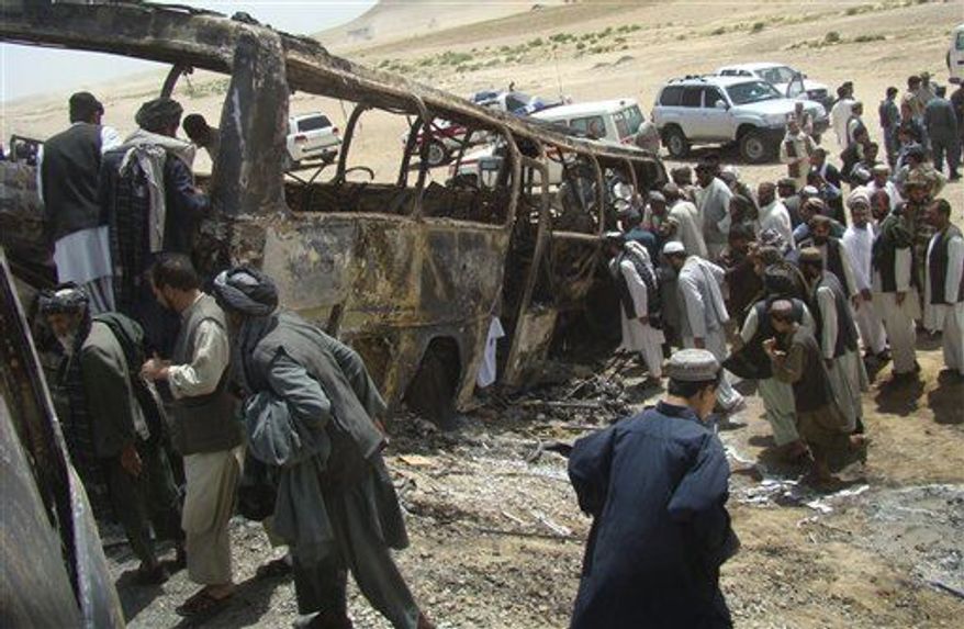 Afghan men surround a burned bus after it collided with the wreckage of a truck that was attacked by Taliban insurgents in Maiwand district, on the highway between Kandahar and Helmand, Afghanistan, Friday, April 26, 2013. Scores of people aboard the bus were killed in the fiery crash, officials said. (AP Photo/Abdul Khaliq Kandahari)