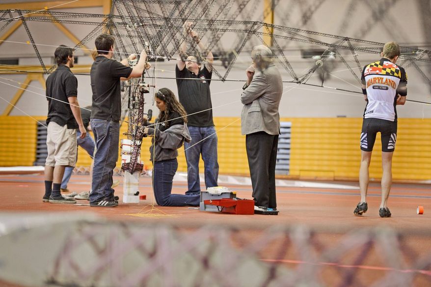 Second year grad student Elizabeth Weiner, right, watches as UMD student and volunteer pilot Colin Gore, center, performs a test flight as students with the University of Maryland attempt to win the $250,000 AHS Sikorsky Prize using their human-powered helicopter at the Prince George's County Sports and Learning Complex in Landover, Md., Sunday, April 28, 2013. The helicopter has already set records for flight time and altitude. (Andrew Harnik/The Washington Times)