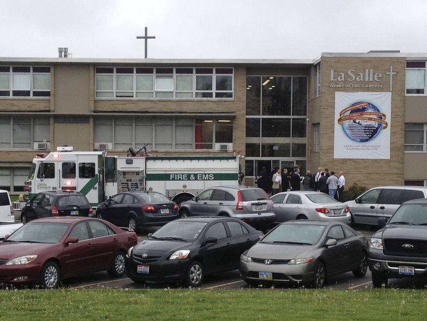 ** FILE ** Police and firefighters gather outside La Salle High School, Monday, April 29, 2013, in Cincinnati, after a high school student pulled out a gun and shot himself in a classroom. The Hamilton County sheriff's office says the youth was taken to a hospital with a self-inflicted wound. (AP Photo/Cincinnati Enquirer, Glenn Hartong)