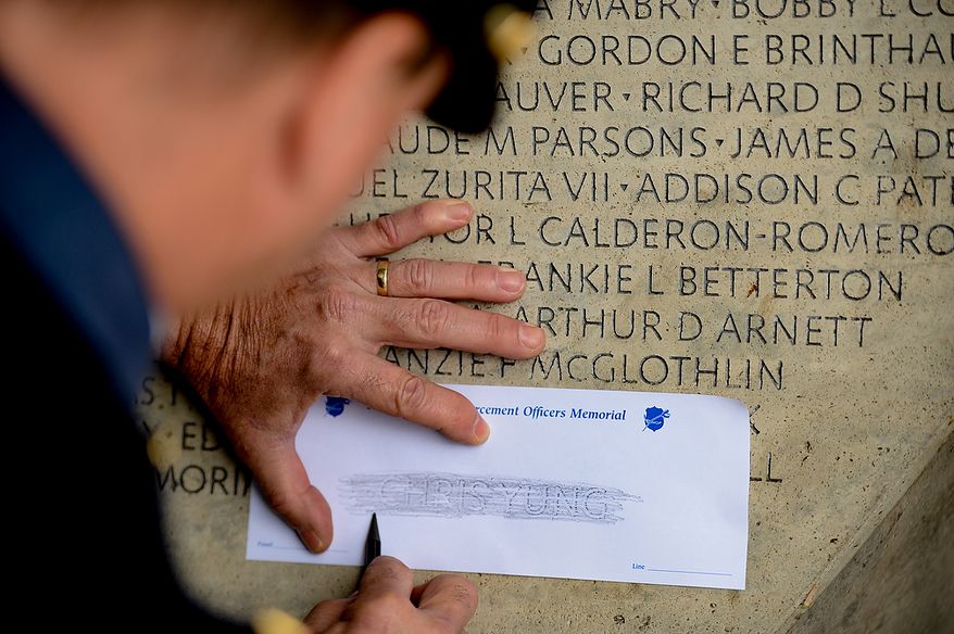 A Prince Williams County motorcycle police officer makes a rubbing of slain Prince William County Police Officer Chris Yung during a ceremony to unveil his name on the wall of the National Law Enforcement Memorial, Washington, D.C., Monday, April 29, 2013. Yung was killed in a motorcycle accident while responding to a separate car crash New Years Eve last year. (Andrew Harnik/The Washington Times)