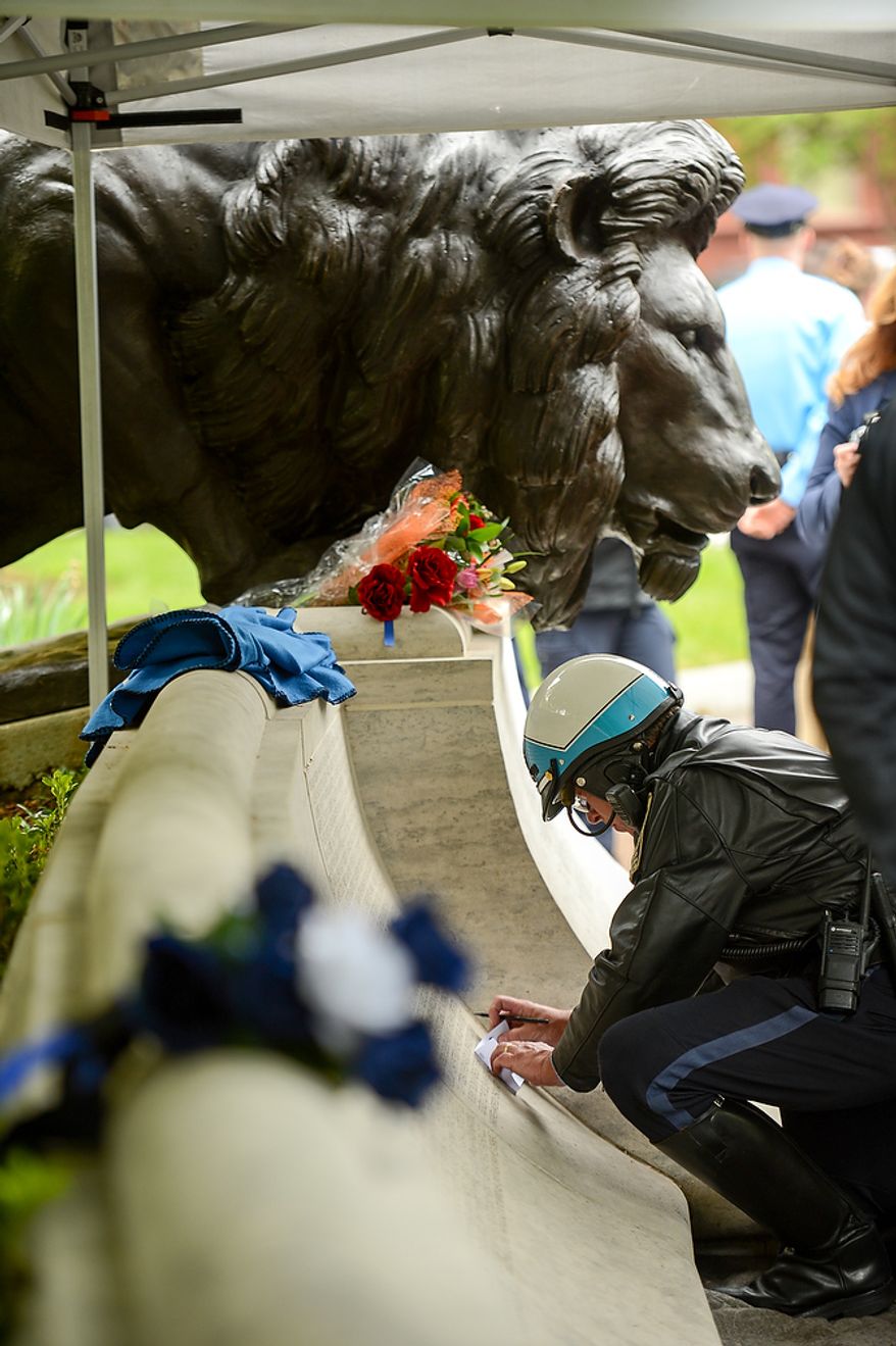 A Prince Williams County motorcycle police officer makes a rubbing of slain Prince William County Police Officer Chris Yung during a ceremony to unveil his name on the wall of the National Law Enforcement Memorial, Washington, D.C., Monday, April 29, 2013. Yung was killed in a motorcycle accident while responding to a separate car crash New Years Eve last year. (Andrew Harnik/The Washington Times)