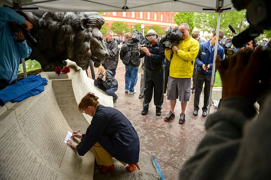 Robin Young makes a rubbing of her slain husband, Prince William County Police Officer Chris Yung during a ceremony to unveil his name on the wall of the National Law Enforcement Memorial, Washington, D.C., Monday, April 29, 2013. Yung was killed in a motorcycle accident while responding to a separate car crash New Years Eve last year. (Andrew Harnik/The Washington Times)