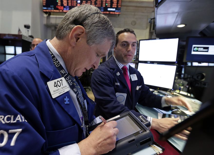 Trader Richard Newman (left) works on the floor of the New York Stock Exchange on May 1, 2013. (Associated Press)