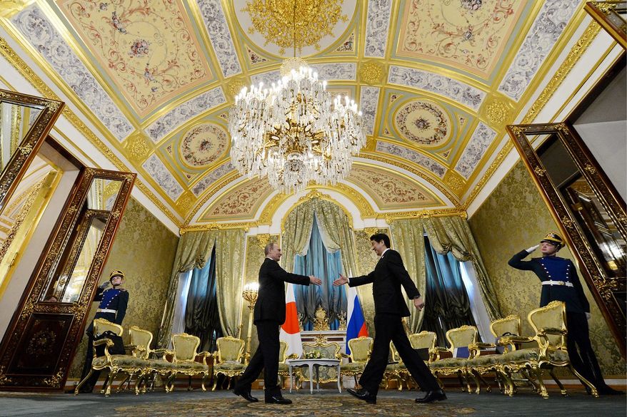 Russian President Vladimir Putin shakes hands with Japanese Prime Minister Shinzo Abe during a meeting in Moscow on Monday. It was the first Russian visit by a Japanese prime minister in 10 years. (Associated Press)