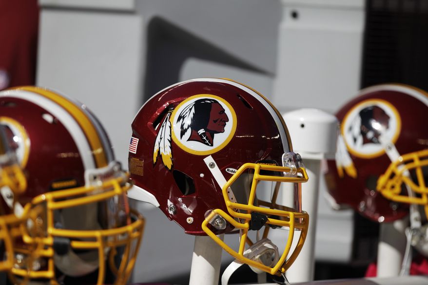 Washington Redskins helmets and logo are shown during the first half of an NFL football game in East Rutherford, N.J. on Oct. 21, 2012. The team's nickname, which some consider a derogatory term for Native Americans, has faced a barrage of criticism. Local leaders and pundits have called for a name change. (Associated Press) **FILE**