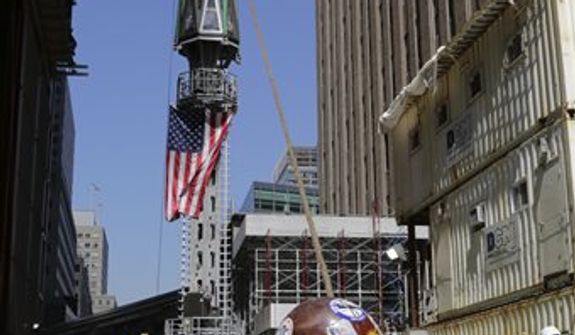 The final piece of the spire is hoisted to the roof of One World Trade Center, Thursday, May 2, 2013 in New York. The piece will be attached to the spire at a later date, capping off the tower at 1,776 feet. (AP Photo/Mark Lennihan)