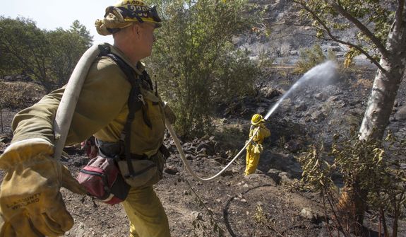 Firefighters douse a burned area along the hillside near the student dorm of  Cal State, Channel Islands in Camarillo, Calif., Thursday, May 2, 2013. (AP Photo/Ringo H.W. Chiu)
