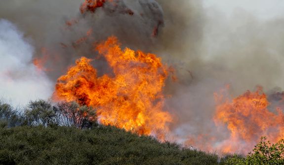 Smoke and fire billows over a hill near Thousand Oaks, Calif. on Thursday, May 2, 2013. Authorities have ordered evacuations of a neighborhood and a university about 50 miles west of Los Angeles where a wildfire is raging close to subdivisions.  (AP Photo/Nick Ut)