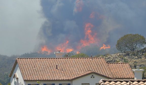 Fire burns behind homes during a wildfire that burned several thousand acres, Thursday, May 2, 2013, in Thousand Oaks, Calif.   (AP Photo/Mark J. Terrill)