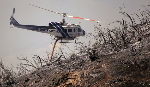 A Kern County Fire helicopter makes a water drop on a hotspot over a hill near Thousand Oaks, Calif. on Thursday, May 2, 2013. Authorities have ordered evacuations of a neighborhood and a university about 50 miles west of Los Angeles where a wildfire is raging close to subdivisions. The blaze on the fringes of Camarillo and Thousand Oaks broke out Thursday morning and was quickly spread by gusty Santa Ana winds. Evacuation orders include California State University, Channel Islands. (AP Photo/Nick Ut)