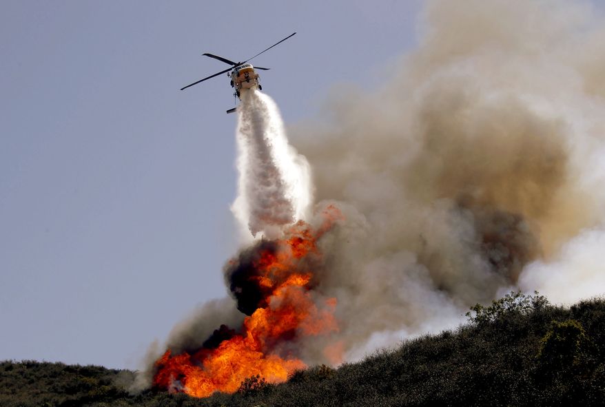 A helicopter makes a water drop on a hotspot over a hill near Thousand Oaks, Calif. on Thursday, May 2, 2013. Authorities have ordered evacuations of a neighborhood and a university about 50 miles west of Los Angeles where a wildfire is raging close to subdivisions. The blaze on the fringes of Camarillo and Thousand Oaks broke out Thursday morning and was quickly spread by gusty Santa Ana winds. Evacuation orders include California State University, Channel Islands. (AP Photo/Nick Ut)