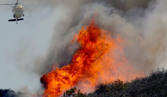 A helicopter makes a water drop on a hotspot over a hill near Thousand Oaks, Calif. on Thursday, May 2, 2013. Authorities have ordered evacuations of a neighborhood and a university about 50 miles west of Los Angeles where a wildfire is raging close to subdivisions. The blaze on the fringes of Camarillo and Thousand Oaks broke out Thursday morning and was quickly spread by gusty Santa Ana winds. Evacuation orders include California State University, Channel Islands. (AP Photo/Nick Ut)