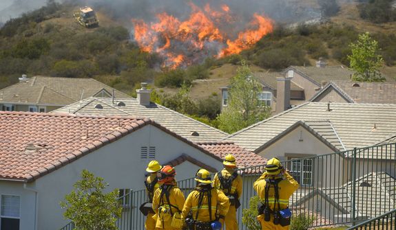 Firefighters from Glendale, Calif., and Pasadena, Calif., stand watch as bulldozers clear a firebreak near a wildfire burning along a hillside near homes in Thousand Oaks, Calif., Thursday, May 2, 2013. A Ventura County Fire Department spokeswoman said the blaze that broke out Thursday morning near Camarillo and Thousand Oaks, 50 miles west of Los Angeles, had spread to over 6,500 acres, forcing evacuations of nearby neighborhoods. (AP Photo/Mark J. Terrill)
