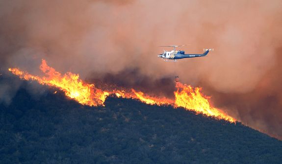 A water dropping helicopter gets ready to make a drop on a fire burring in Point Mugu State Park during a wildfire that burned several thousand acres, Thursday, May 2, 2013, in Ventura County, Calif.   (AP Photo/Mark J. Terrill)