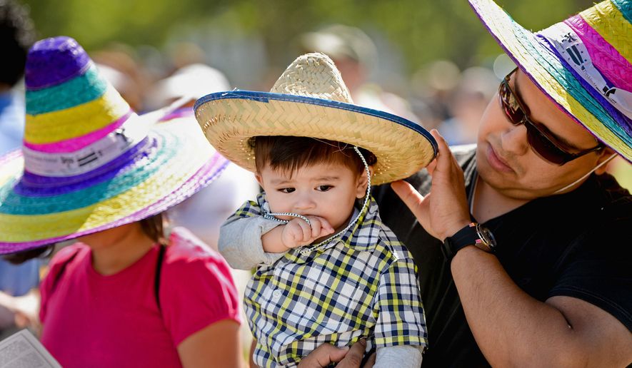 Erick Doledo of Woodbridge, Va., holds his son Erick Jr., and listens live music with his daughter Samantha, 12, left, during the annual Cinco de Mayo celebration on the National Mall, Washington, D.C., Sunday, May 5, 2013. (Andrew Harnik/The Washington Times)