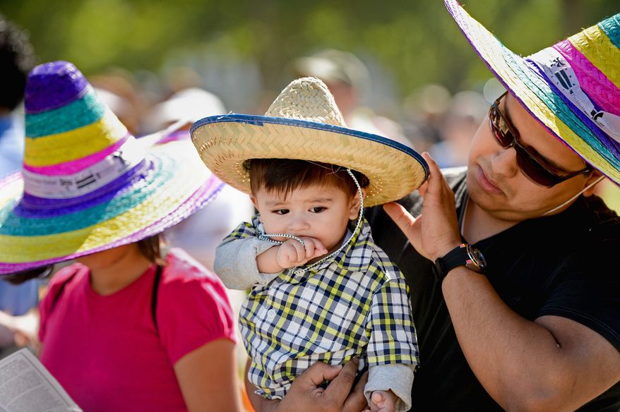 Erick Doledo of Woodbridge, Va., holds his son Erick Jr., and listens live music with his daughter Samantha, 12, left, during the annual Cinco de Mayo celebration on the National Mall, Washington, D.C., Sunday, May 5, 2013. (Andrew Harnik/The Washington Times)