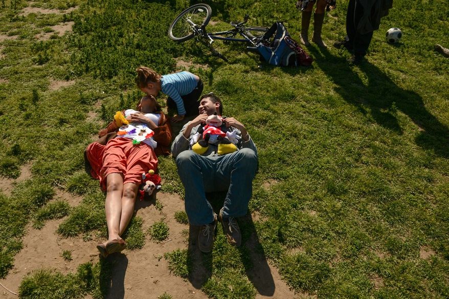 A mother who didn't wish to be identified gets a kiss from her daughter as she relaxes with her friend at the Cinco de Mayo celebration on the Mall on Sunday. (Andrew Harnik/The Washington Times)