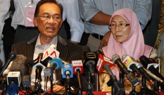 Malaysian opposition leader Anwar Ibrahim (left) and his wife, Wan Azizah, speak during a press conference at a hotel in Kuala Lumpur on Monday, May 6, 2013. Malaysia&#39;s governing coalition fended off a tough election challenge to extend its 56-year rule. (AP Photo/Vincent Thian)