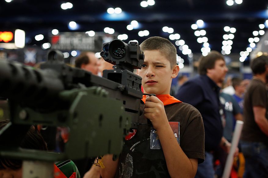 13-year-old Jacob La looks down the sight of a mounted machine gun, during the NRA Annual Meeting of Members at the National Rifle Association's 142 Annual Meetings and Exhibits in the George R. Brown Convention Center Saturday, May 4, 2013, in Houston. National Rifle Association leaders told members Saturday that the fight against gun control legislation is far from over, with battles yet to come in Congress and next year's midterm elections, but they vowed that none in the organization will ever have to surrender their weapons. (AP Photo/Houston Chronicle, Todd Spoth)