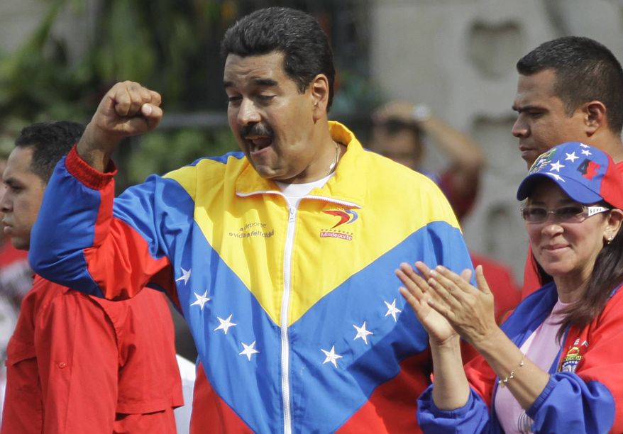 ** FILE ** Venezuela's President Nicolas Maduro holds his fist to supporters as his companion Cilia Flores applauds during a pro-government May Day march in Caracas, Venezuela, Wednesday, May 1, 2013. (AP Photo/Ariana Cubillos)