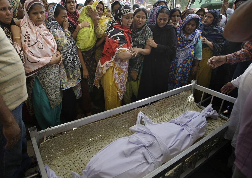 ** FILE ** Pakistani women mourn on Sunday, May 5, 2013, in Karachi, Pakistan, during the funeral of a child killed in a bombing on Saturday. The two blasts also killed two others near the office of a political party critical of the Taliban, heightening tensions ahead of the country's historic May 11 election. (AP Photo/Fareed Khan)