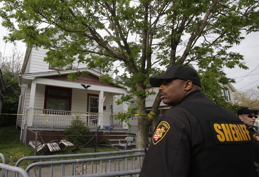 On Tuesday, May 7, 2013, a sheriff's deputy stands outside a Cleveland house from which three women escaped on Monday after being held in captivity for about a decade, police said. (AP Photo/Tony Dejak)