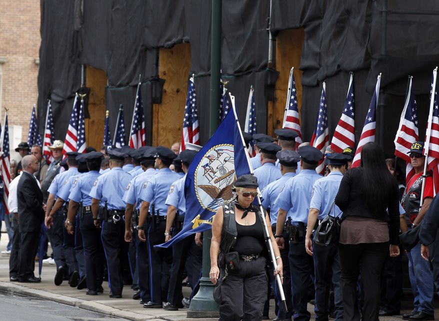 **FILE** Philadelphia police officers go inside as a woman carries a U.S. Navy flag, at services for U.S.Navy Petty Officer 1st Class Michael Joseph Strange, a cryptology technician, at the Cathedral Basilica of Saints Peter and Paul, on Aug. 18, 2011, in Philadelphia. Strange was assigned to the Navy SEAL team whose Chinook helicopter was shot down Aug. 6 by a rocket-propelled grenade in what has become the deadliest single loss for U.S. forces in the decade-long war in Afghanistan. (Associated Press)