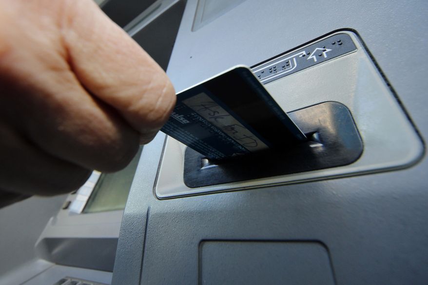 **FILE** A person inserts a debit card into an ATM machine in Pittsburgh on Jan. 5, 2013. (Associated Press)