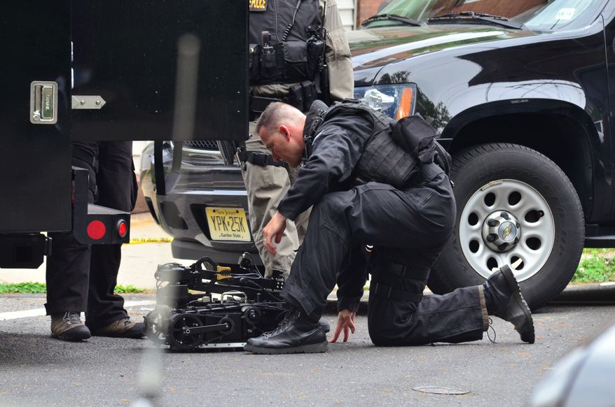 A New Jersey State Police swat team member readies a robot to enter a home in which a man had barricaded himself on Friday, May 10, 2013, in Trenton, N.J. (AP Photo/The Trentonian, Scott Ketterer)