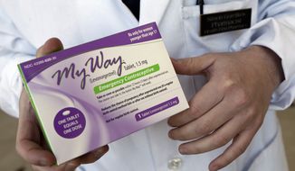 **FILE** Pharmacist Simon Gorelikov holds a generic emergency contraceptive at the Health First Pharmacy in Boston on May 2, 2013. (Associated Press)