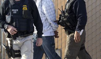 **FILE** Immigration and Customs Enforcement (ICE) agents take a suspect into custody on March 30, 2012, as part of a nationwide immigration sweep in Chula Vista, Calif. (Associated Press)