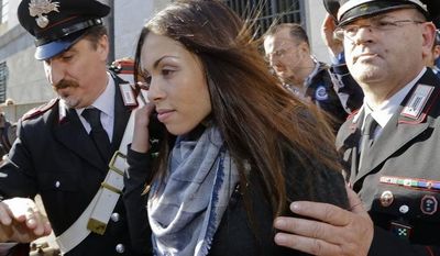Karima el-Mahroug&#x27;s is escorted outside the Milan&#x27;s Law court by two Carabinieri police officers after giving her testimony at the trial of three former Berlusconi aides accused with procuring her and other woman for prostitution, in Milan, Italy, Friday, May 17, 2013. Silvio Berlusconi&#x27;s private disco featured not only aspiring show girls performing striptease acts as sexy nuns and nurses, but also dressed as President Barack Obama. (AP Photo/Luca Bruno)