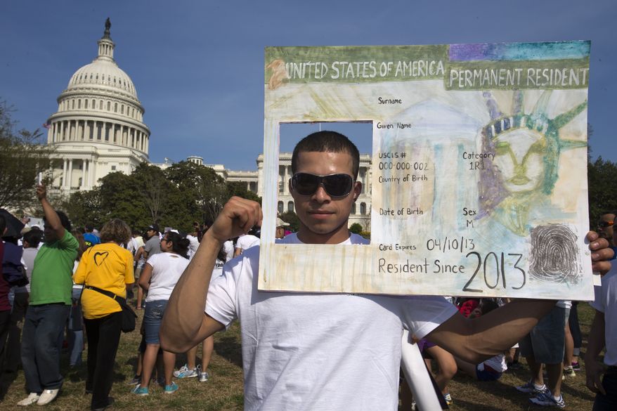 **FILE** Roberto Morales, 25, holds a sign representing a permanent resident card while attending the "Rally for Citizenship" on Capitol Hill on April 10, 2013, in support of immigration reform. (Associated Press)