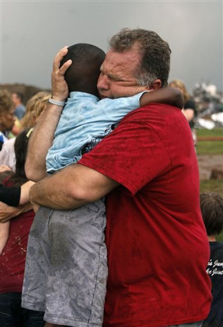A teacher hugs a child at Briarwood Elementary school after a tornado destroyed the school in south Oklahoma City, Monday, May 20, 2013. A monstrous tornado roared through the Oklahoma City suburbs, flattening entire neighborhoods with winds up to 200 mph, setting buildings on fire and landing a direct blow on an elementary school. (AP Photo/The Oklahoman, Paul Hellstern)