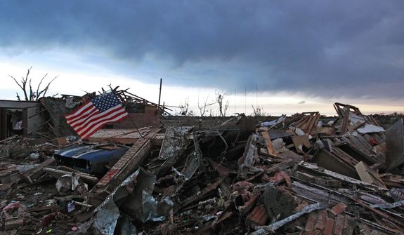 An American flag blows in the wind at sunrise atop the rubble of a destroyed home a day after a tornado moved through Moore, Okla., Tuesday, May 21, 2013. (AP Photo/Brennan Linsley)

