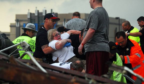 Emergency workers pull out a woman that was trapped in a building that was destroyed off of 4th Street and Interstate 35 after a tornado ripped through Moore, Okla., Monday May 20, 2013. (AP Photo/ The Transcript, Kyle Phillips )