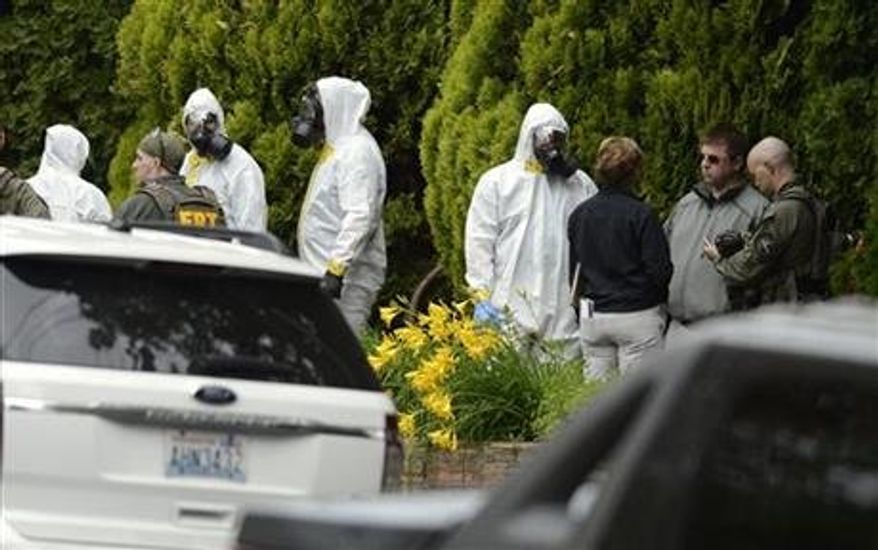 During the execution of a search warrant, members of the Joint Federal Haz-Mat Team, FBI, and local law enforcement gather in front of the Osmun Apartments near the intersection of First Avenue and Oak Street in Browne's Addition on Saturday, May 18, 2013 in Spokane, Wash. The search warrant is in connection with ricin-laced letters intercepted at a Post Office facility in Spokane earlier in the week. (Associated Press)