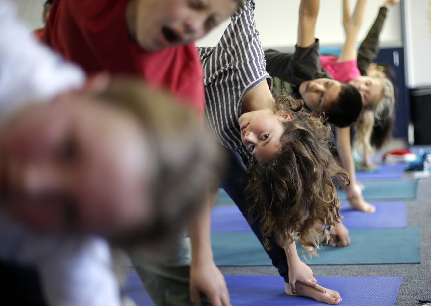 Students hold their position during a yoga class at Capri Elementary School in Encinitas, Calif., on Wednesday, Dec. 11, 2012. (AP Photo/Gregory Bull)