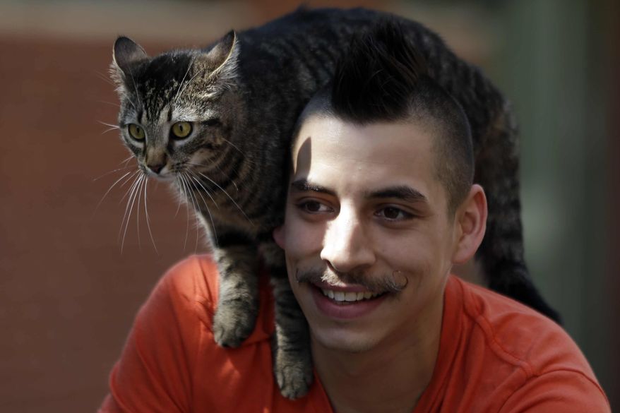 In this Tuesday, May 21, 2013, photo, bicyclist Rudi Saldia and his cat Mary Jane pose for a portrait during an interview with The Associated Press in Philadelphia. (AP Photo/Matt Rourke)