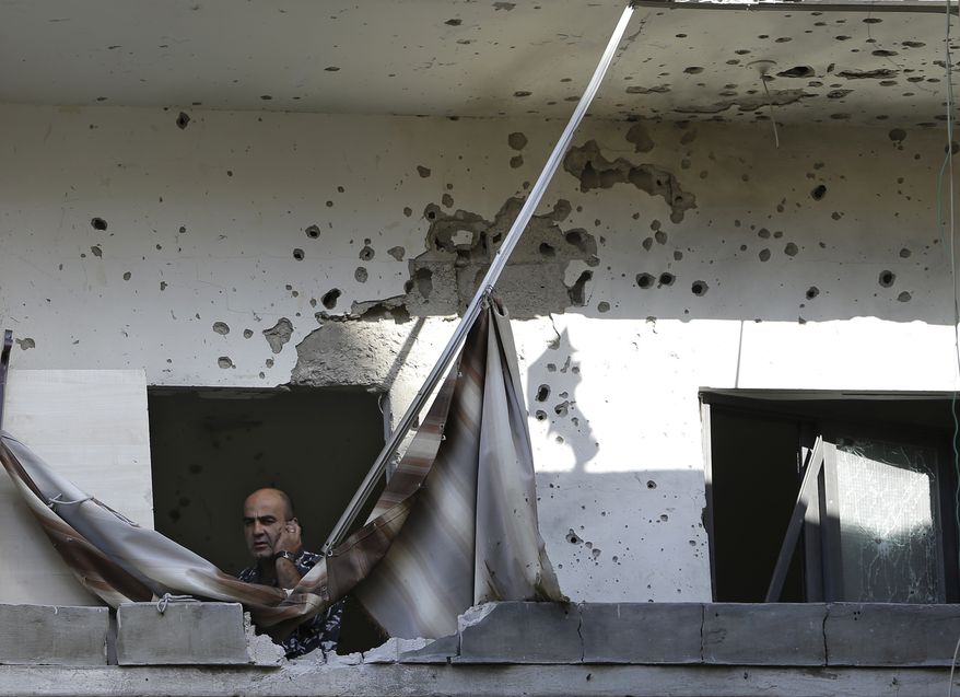 A Lebanese policeman speaks on his phone as he stands at a damaged balcony where a rocket struck an apartment in a building in the Chiyah district south of Beirut on Sunday, May 26, 2013. Rockets that slammed into two Hezbollah stronghold neighborhoods wounded at least four people. (AP Photo/Hussein Malla)