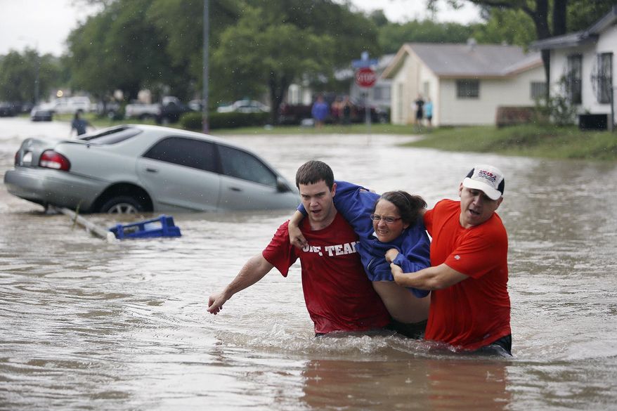 Marco Fairchild (left) and Gary Garza (right) help Sueann Schaller from her car on Saturday, May 25, 2013, in San Antonio after she drove it into floodwaters in the Westwood Village neighborhood. (AP Photo/San Antonio Express-News, Lisa Krantz)