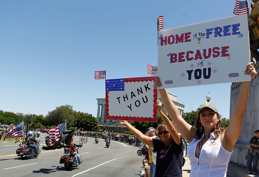 Motorcyclists ride across the Memorial Bridge into Washington as Jen Caryl, right, and her mother Connie of Dale City, Va., hold appreciative signs Sunday, May 26, 2013, during the annual Rolling Thunder "Ride for Freedom" parade ahead of Monday's Memorial Day celebration. (AP Photo/Molly Riley)