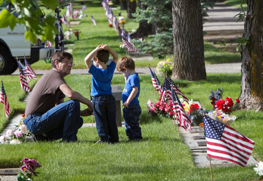 Jim Ransom, of Boise, shows his father's grave site to foster children Matthew, 5, and Nicholas, 3, Monday May 27, 2013 at Dry Creek Cemetery in northwest Boise. Many people celebrated Memorial Day visiting the grave sites of deceased loved ones and decorating the memorials with flowers and flags.